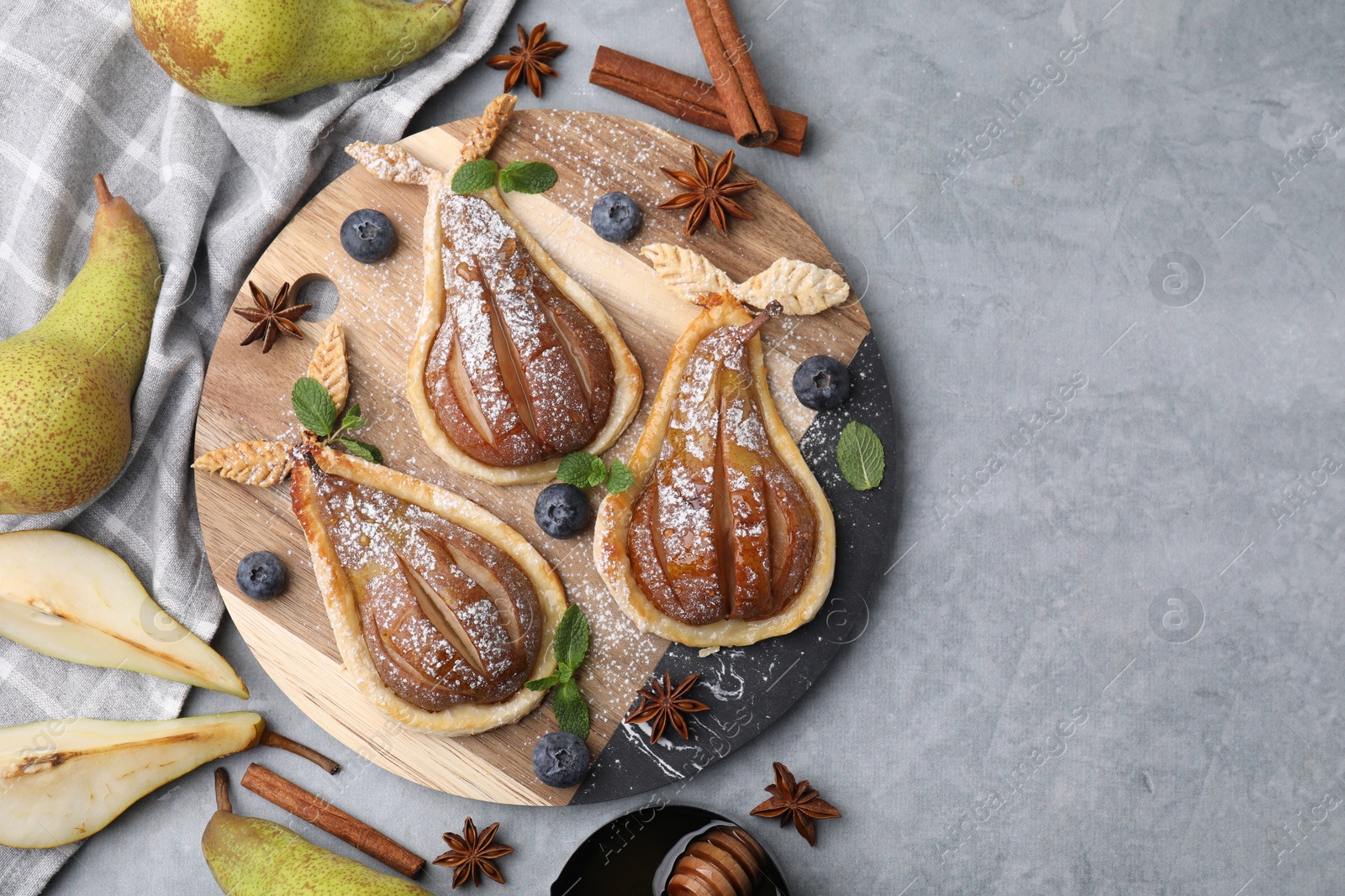 Photo of Delicious pears baked in puff pastry with powdered sugar served on grey table, flat lay. Space for text