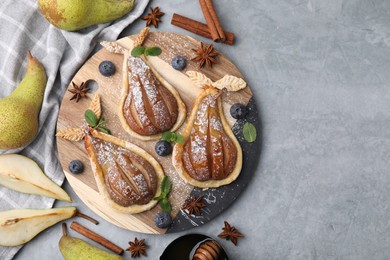 Delicious pears baked in puff pastry with powdered sugar served on grey table, flat lay. Space for text