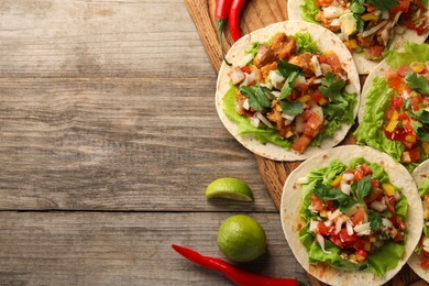 Photo of Delicious tacos with vegetables, meat and lime on wooden table, flat lay. Space for text