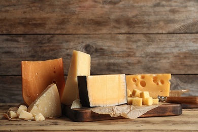 Photo of Different types of delicious cheese on table against wooden background