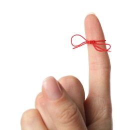 Woman showing index finger with tied red bow as reminder on white background, closeup