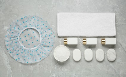 Flat lay composition with shower cap and toiletries on grey marble background