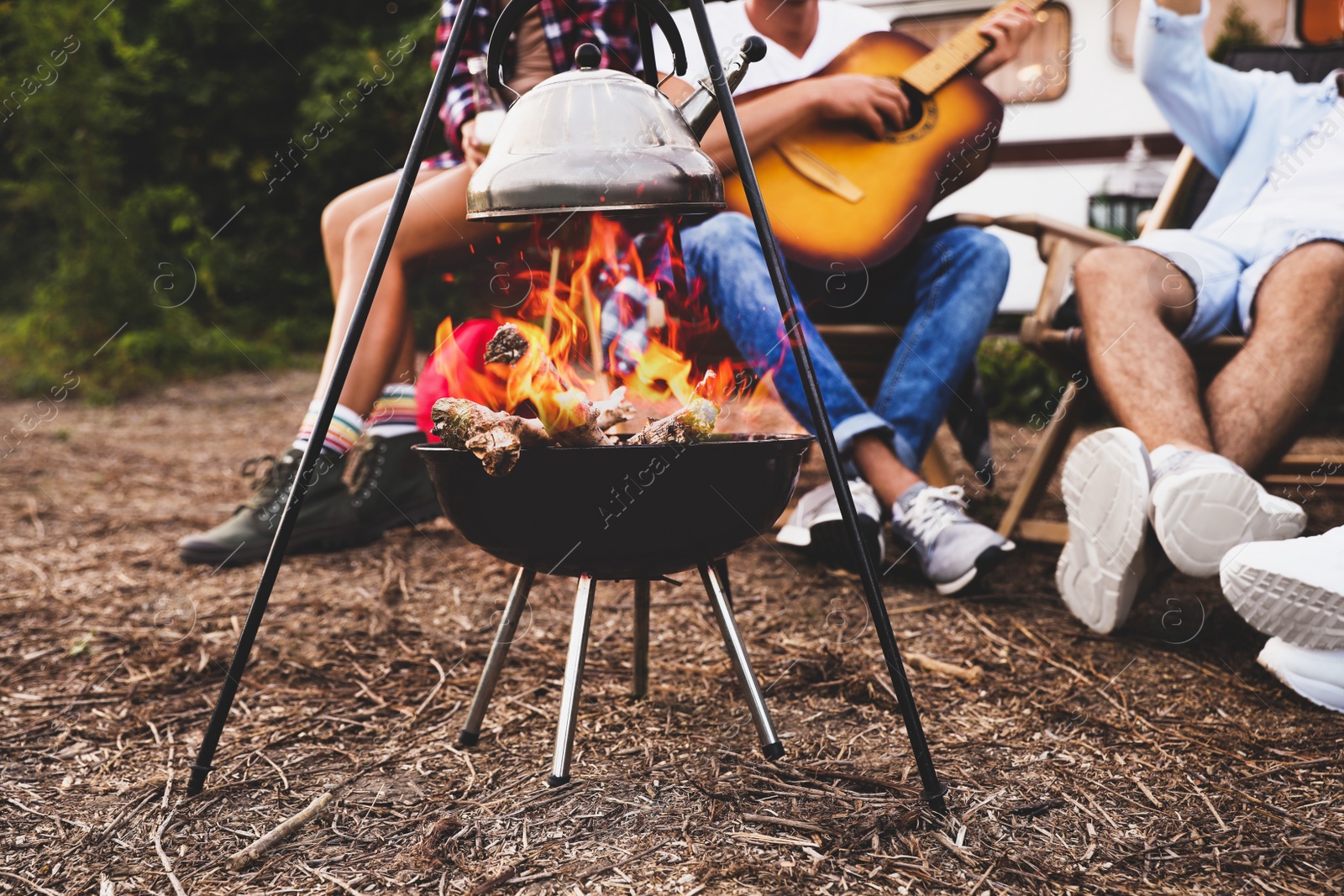 Image of Friends resting together near bonfire, closeup view. Camping season