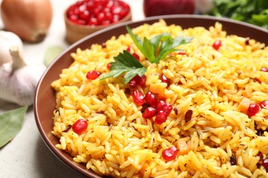 Photo of Tasty rice pilaf with pomegranate grains on table, closeup