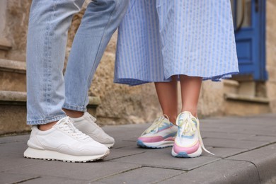 Photo of Woman and man wearing stylish sneakers outdoors closeup