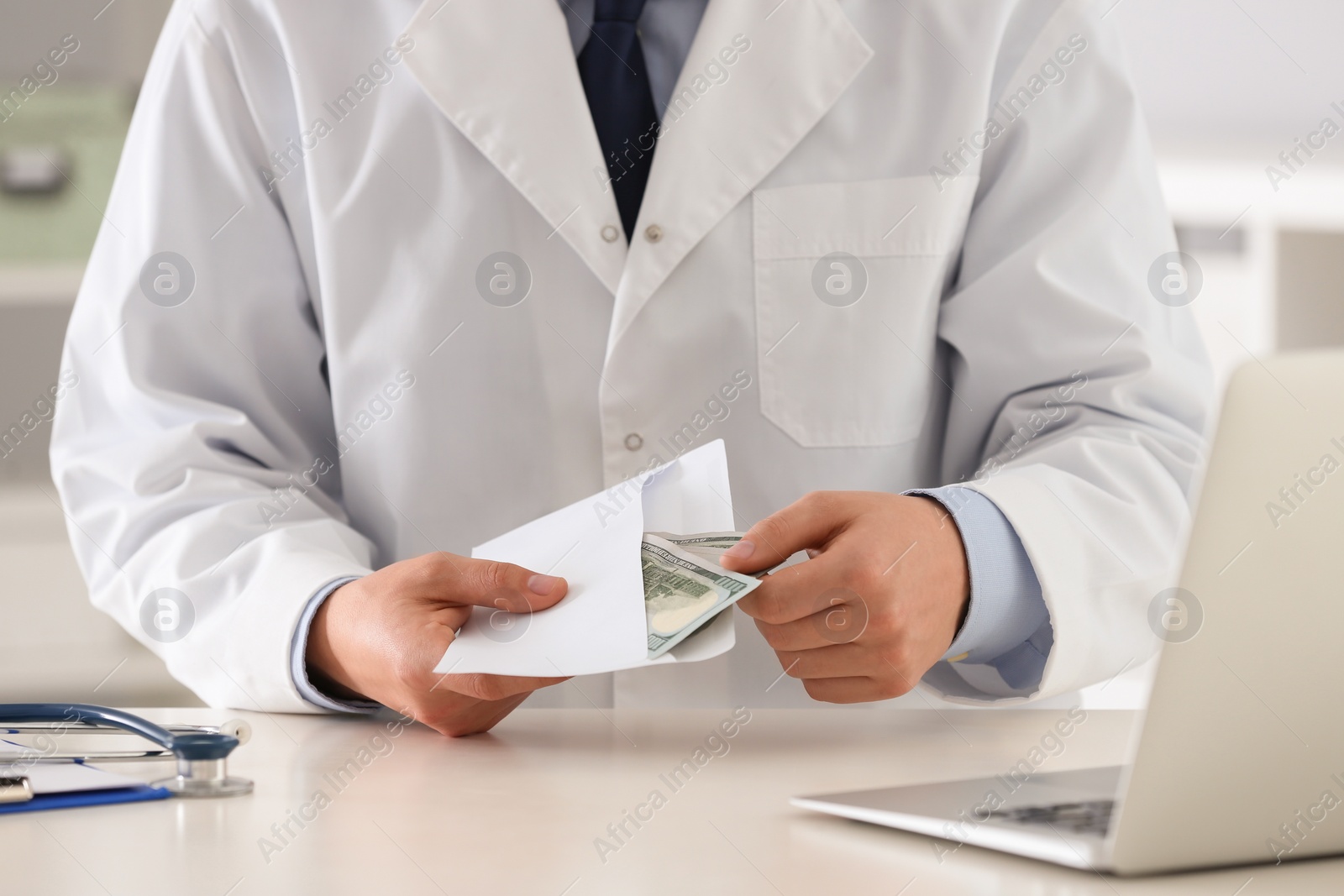 Photo of Doctor with bribe at desk in clinic, closeup. Corrupted medicine