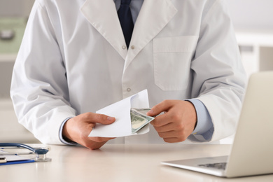 Doctor with bribe at desk in clinic, closeup. Corrupted medicine