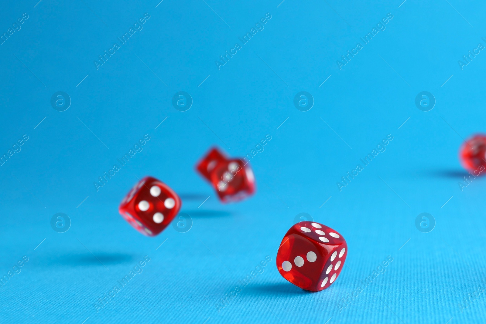 Photo of Many red game dices falling on light blue background