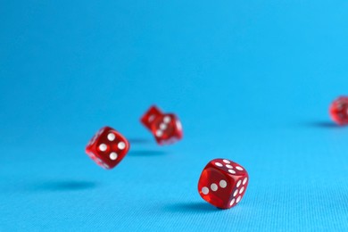 Photo of Many red game dices falling on light blue background