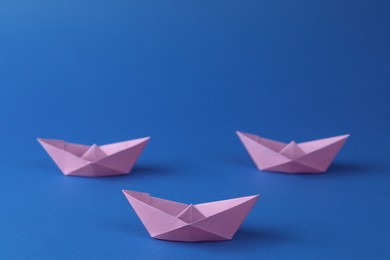 Photo of Handmade violet paper boats on blue background. Origami art