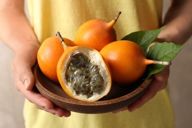 Photo of Woman with ripe granadillas on beige background, closeup
