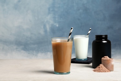 Photo of Glasses with different protein shakes and powder on table. Space for text