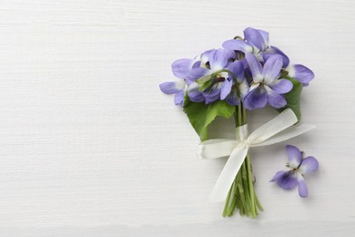 Beautiful wild violets and space for text on white wooden table, top view. Spring flowers