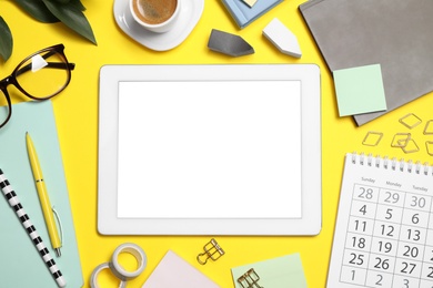 Flat lay composition with tablet and stationery on yellow background