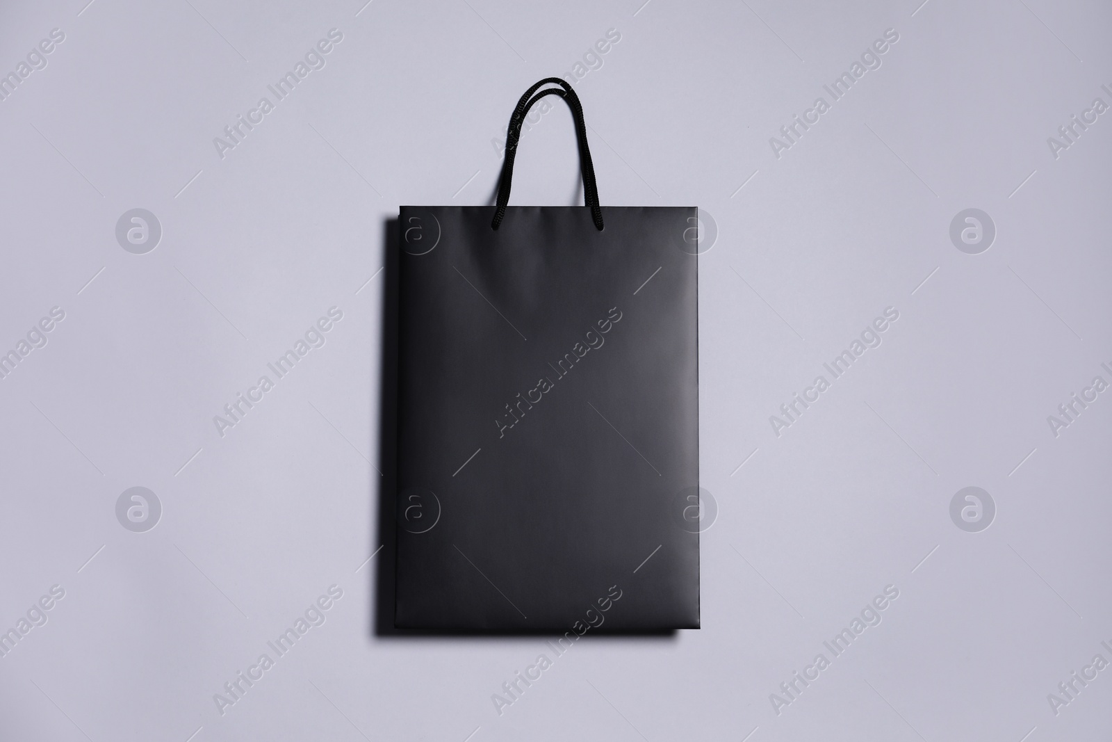 Photo of One black paper shopping bag on grey background, top view