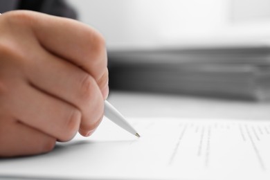 Photo of Man signing document at table in office, closeup