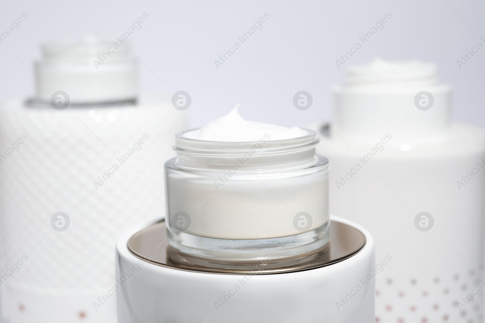 Photo of Open jars of cream on display against light background, closeup