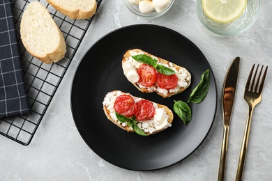 Tasty fresh tomato bruschettas on grey marble table, flat lay