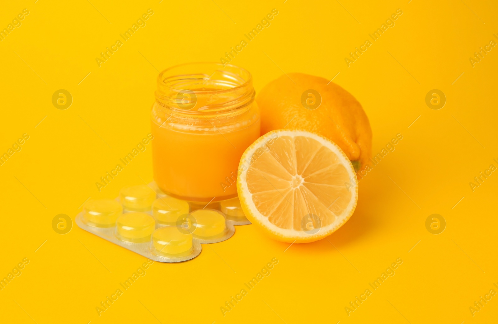 Photo of Cough drops, fresh lemons and honey on yellow background