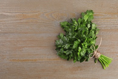 Bunch of fresh green parsley leaves on light wooden table, top view. Space for text