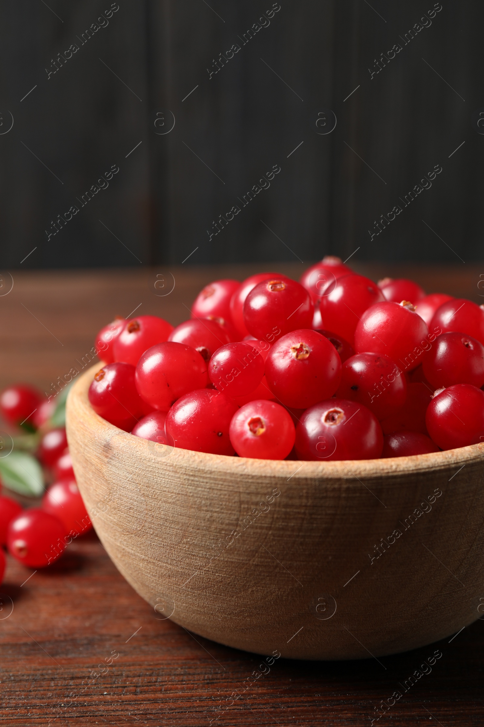 Photo of Tasty ripe cranberries on brown wooden table, closeup