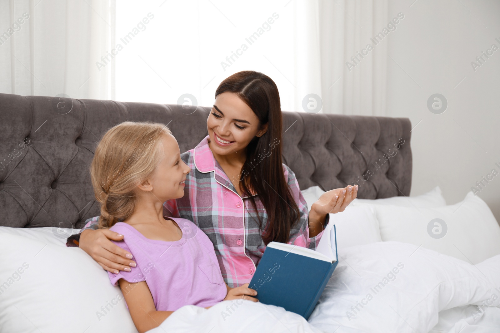 Photo of Mother and daughter reading book in bed. Help concept