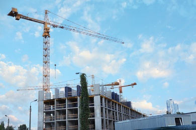 Photo of Construction crane and unfinished building against blue sky. Space for text