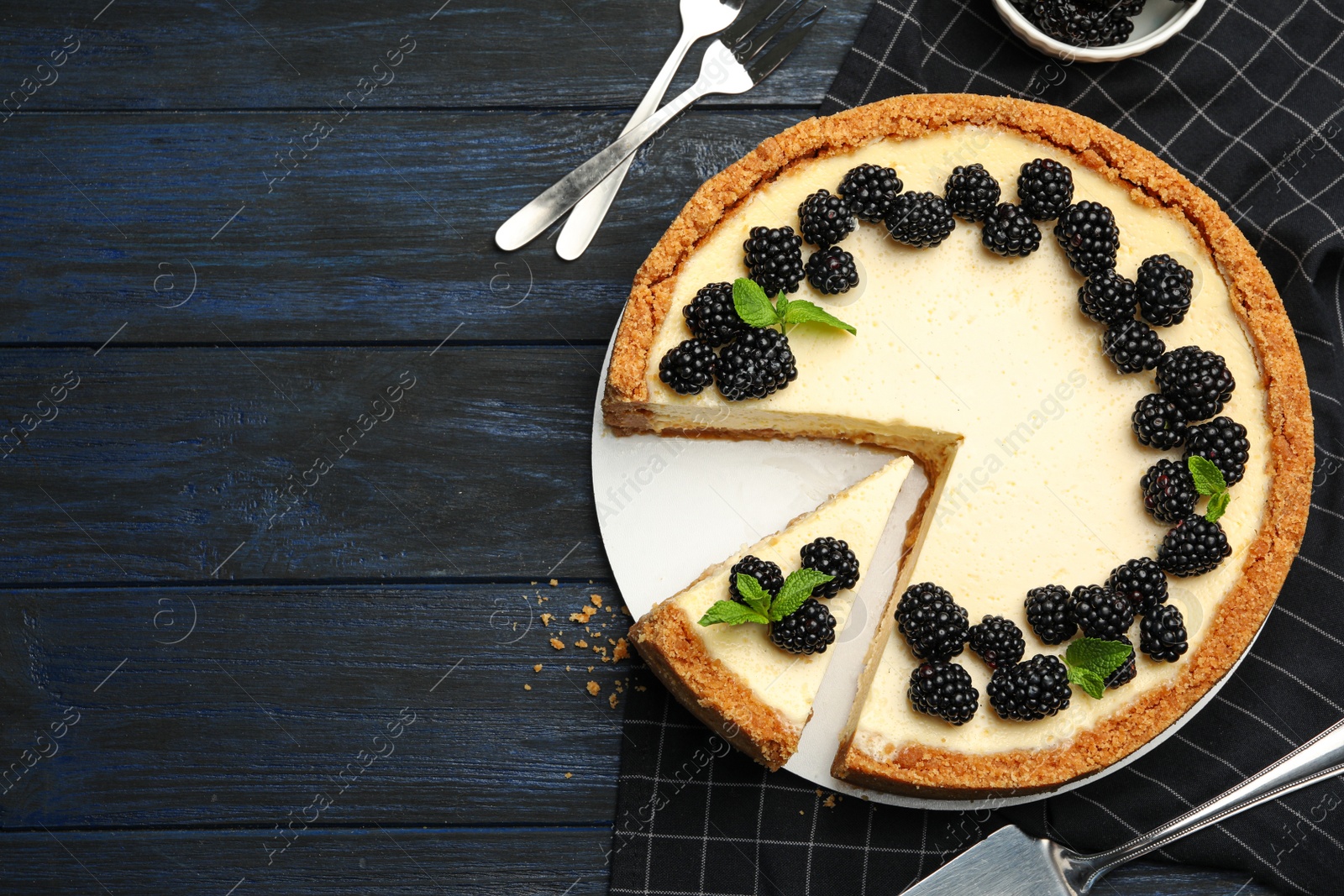 Photo of Sliced delicious cheesecake with blackberries on dark wooden background, flat lay. Space for text