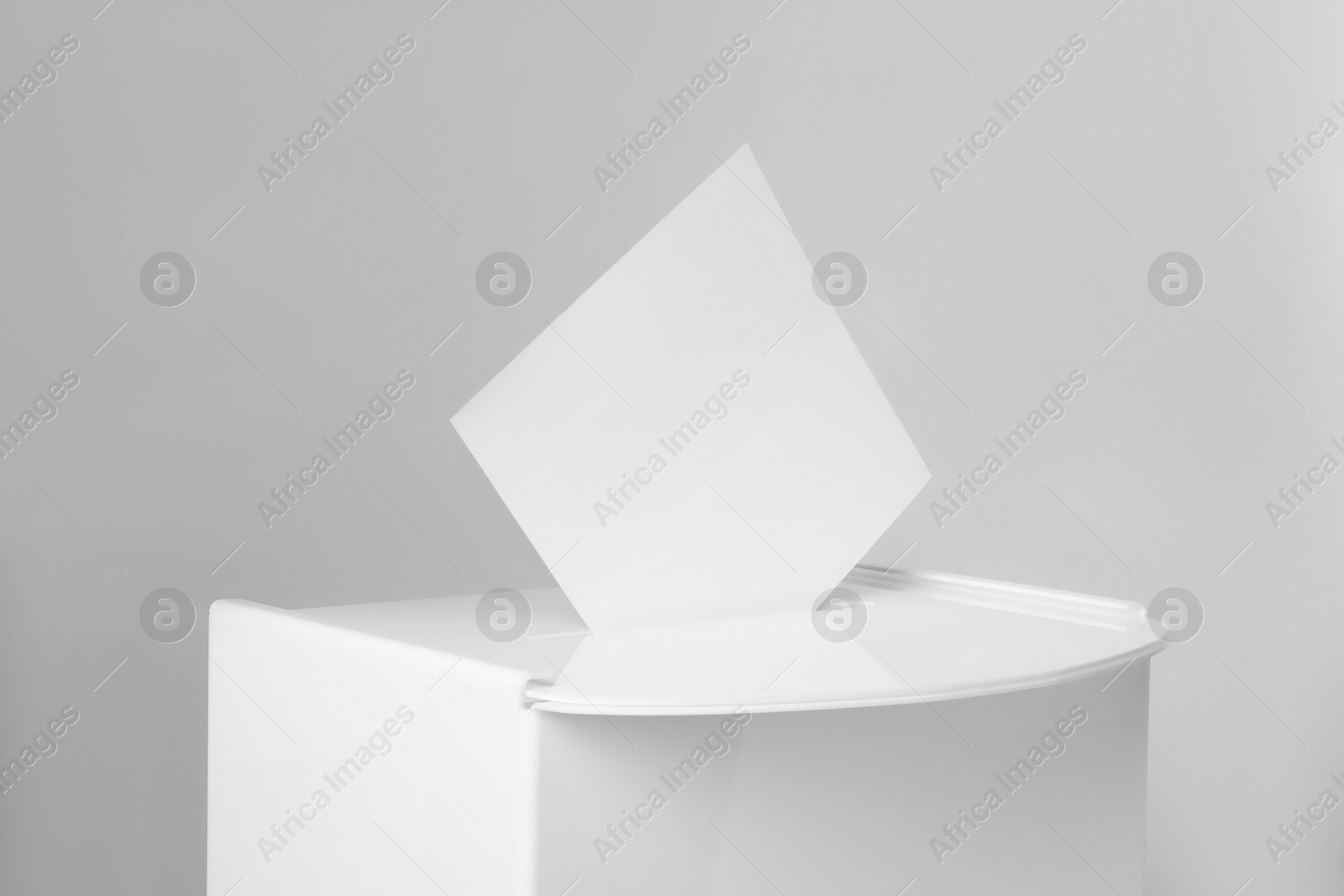 Photo of Ballot box with vote on light grey background, closeup. Election time