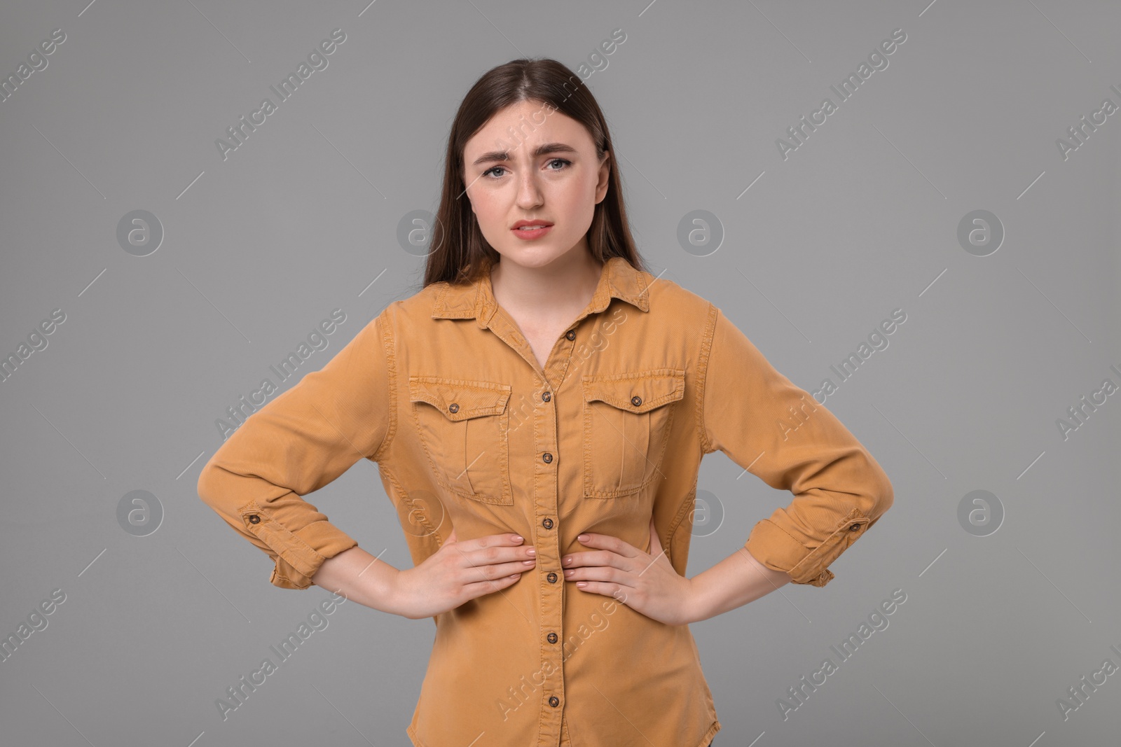 Photo of Young woman suffering from stomach pain on grey background