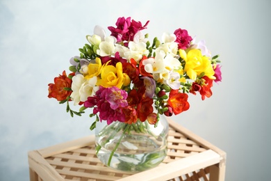 Photo of Bouquet of spring freesia flowers in vase on color background