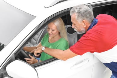 Photo of Senior man teaching his wife to drive car. Loving couple on road trip