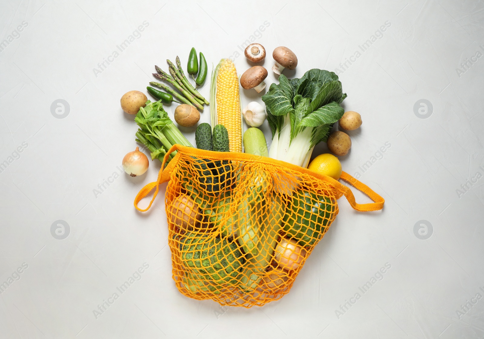 Photo of Fresh vegetables in eco mesh bag on white background, flat lay