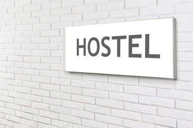 Image of HOSTEL sign board on white brick wall