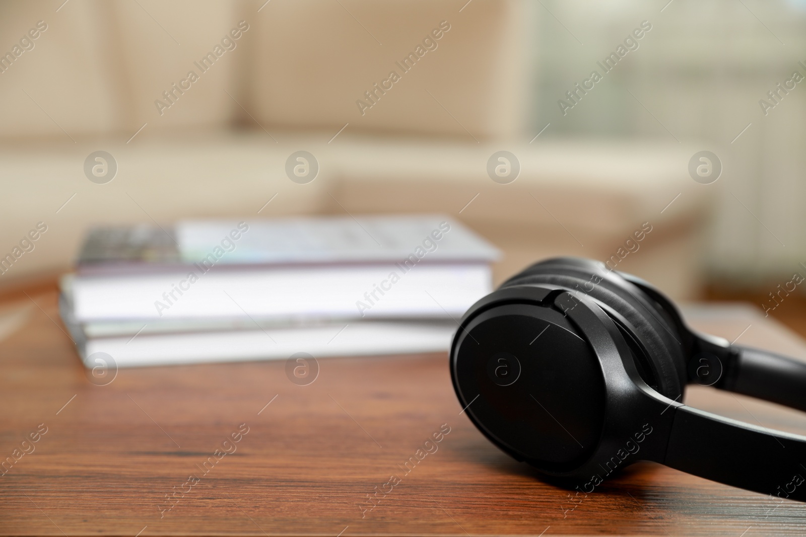 Photo of Modern wireless headphones on wooden table indoors, closeup. Space for text