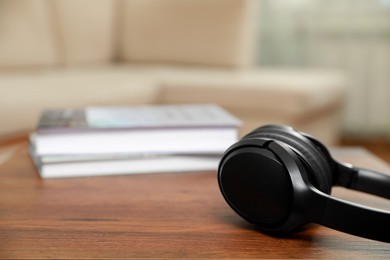 Modern wireless headphones on wooden table indoors, closeup. Space for text