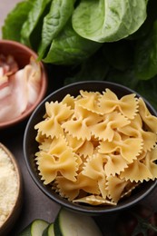 Photo of Raw pasta, bacon and fresh ingredients on brown table