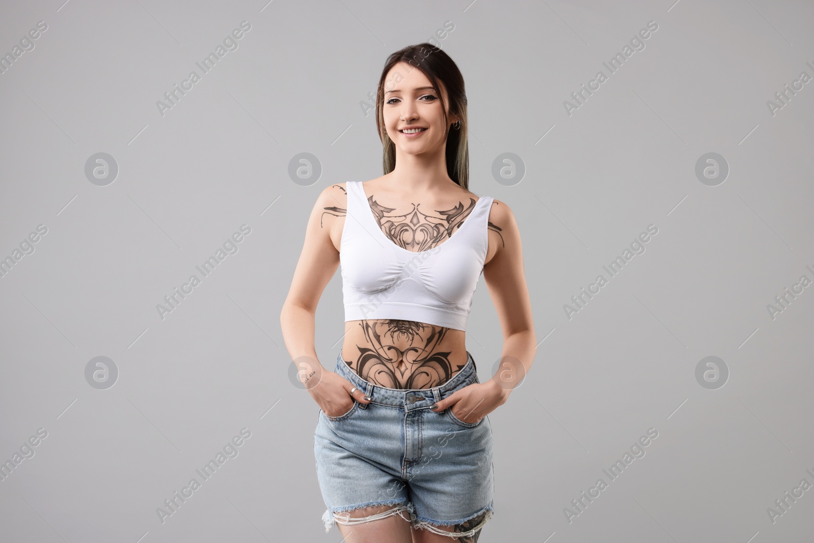 Photo of Portrait of smiling tattooed woman on grey background