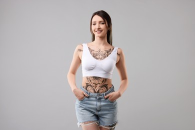 Photo of Portrait of smiling tattooed woman on grey background