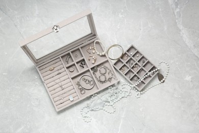 Photo of Jewelry boxes with many different accessories on light grey table, flat lay