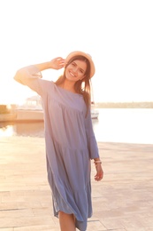 Young woman walking on pier at sunset light