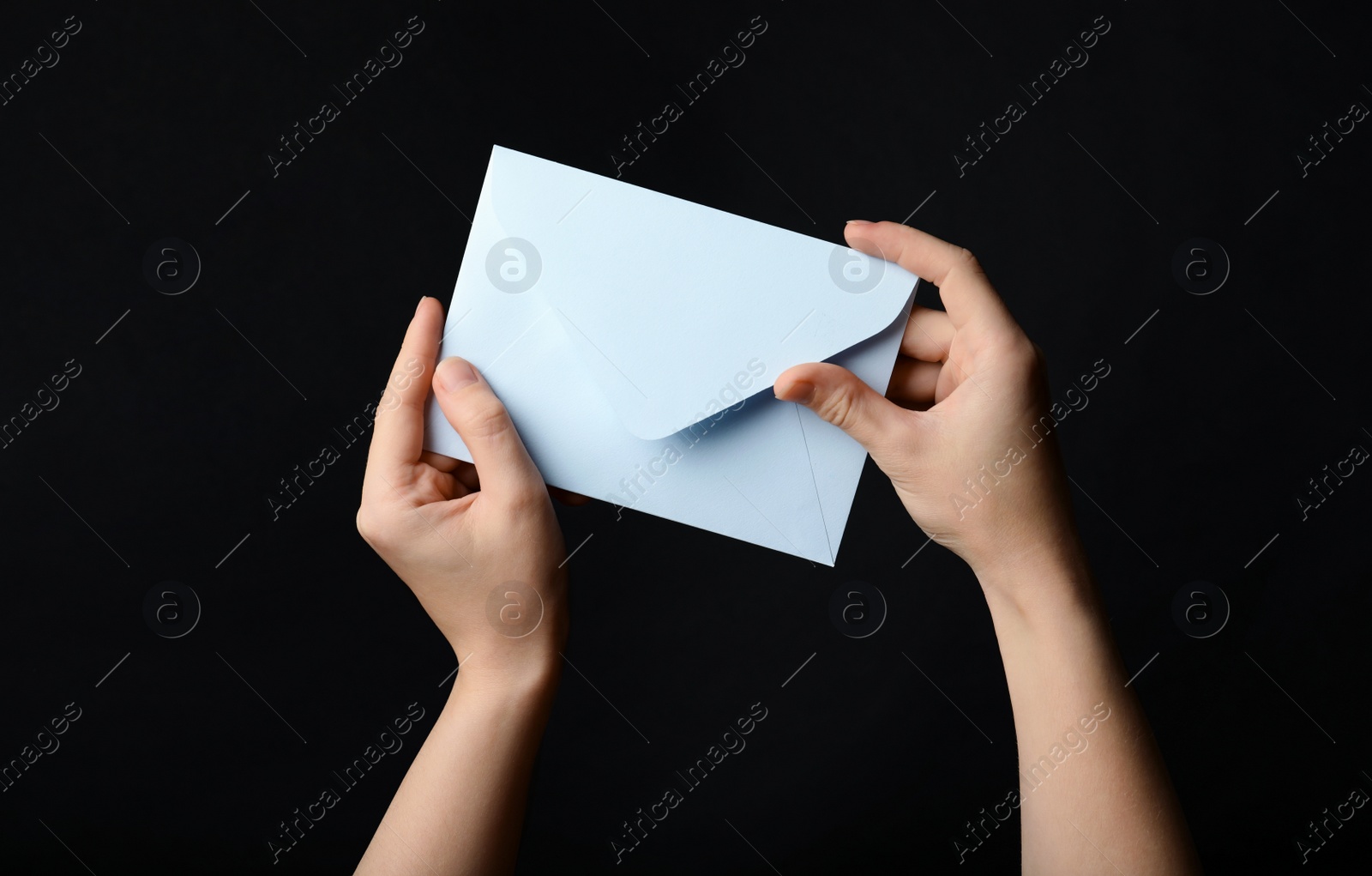 Photo of Woman holding white paper envelope on black background, closeup