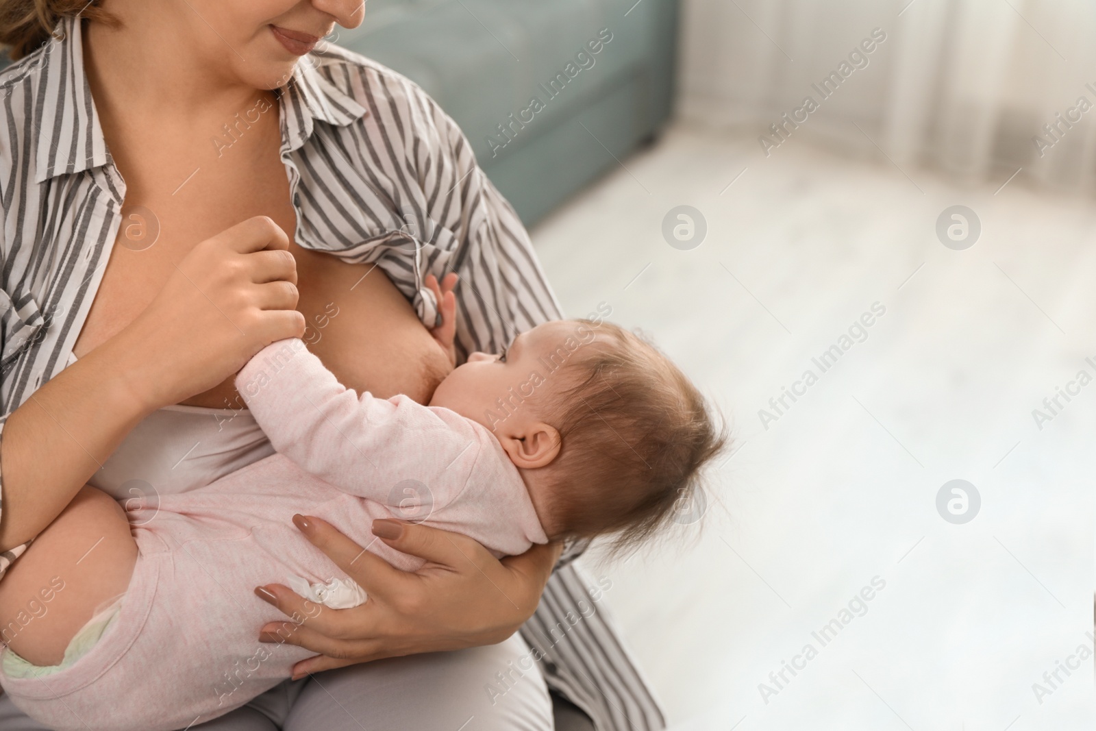 Photo of Young woman breastfeeding her baby at home