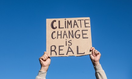 Photo of Young woman with poster protesting against climate change outdoors, closeup