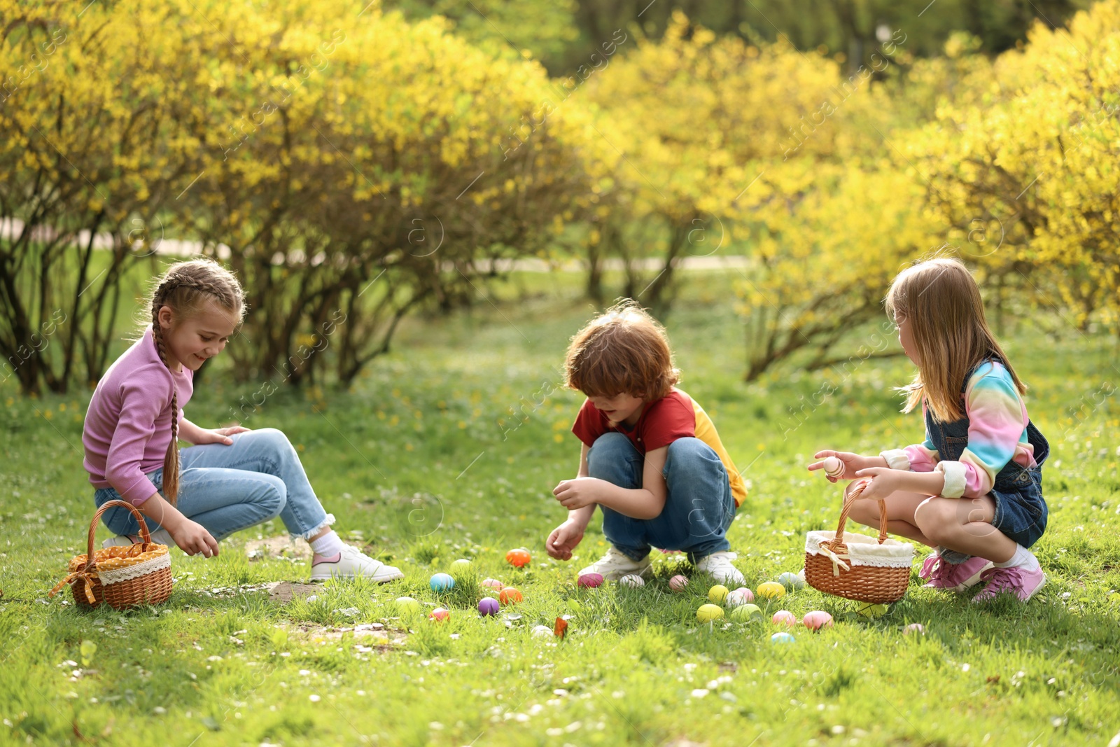 Photo of Easter celebration. Cute little children hunting eggs outdoors