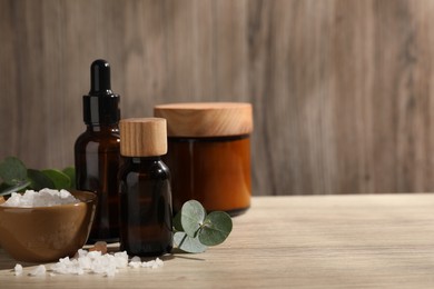 Composition with spa products and eucalyptus leaves on wooden table, space for text