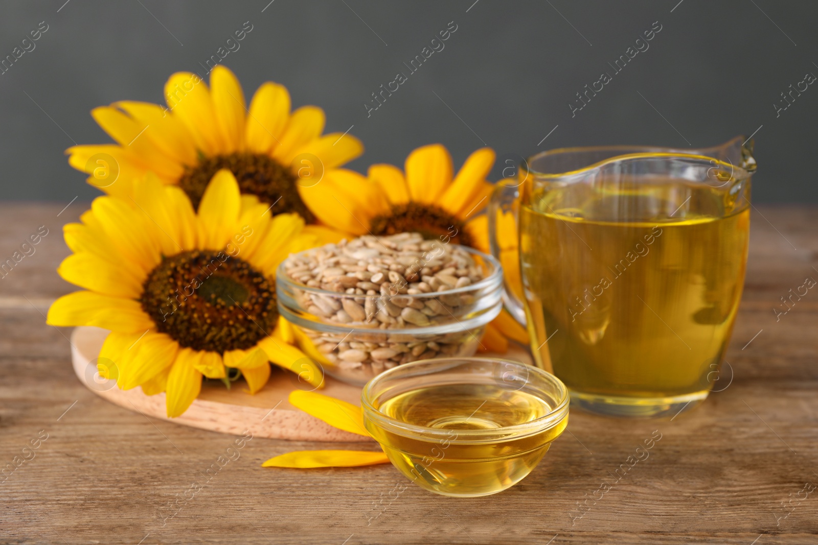 Photo of Sunflowers, oil and seeds on wooden table