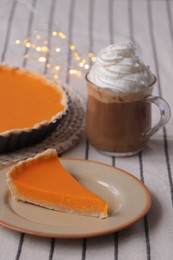 Photo of Fresh homemade pumpkin pie and cup of cocoa with whipped cream on table