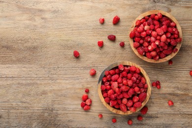 Fresh wild strawberries in bowls on wooden table, flat lay. Space for text