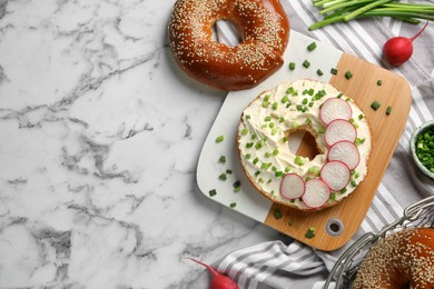 Photo of Delicious bagel with cream cheese, green onion and radish on white marble table, flat lay. Space for text